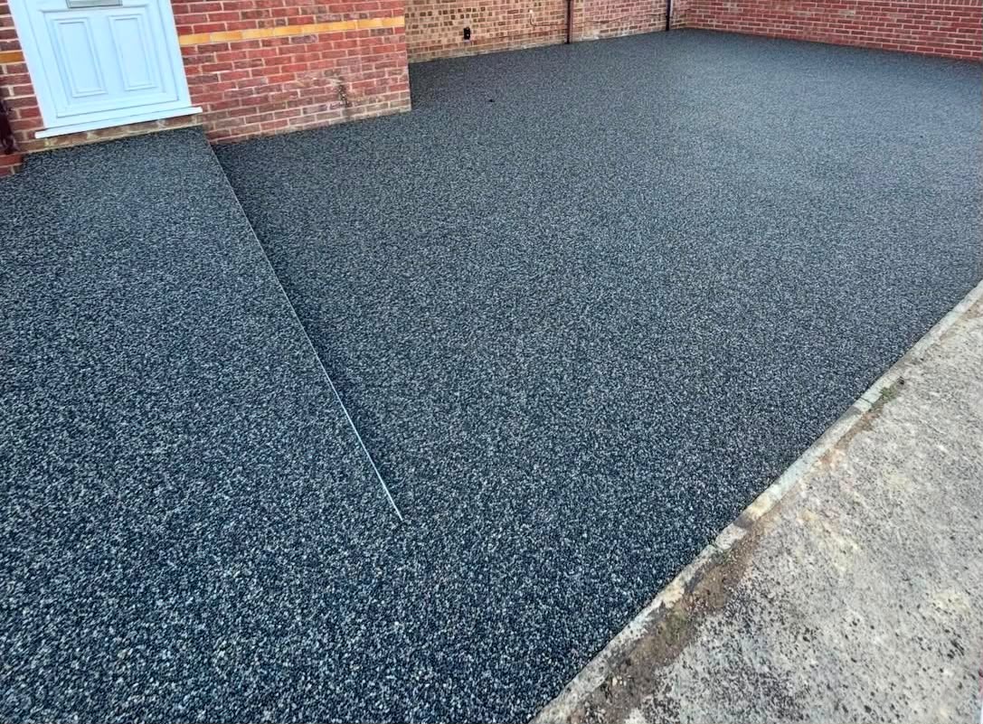 Charcoal resin driveway beside a brick house