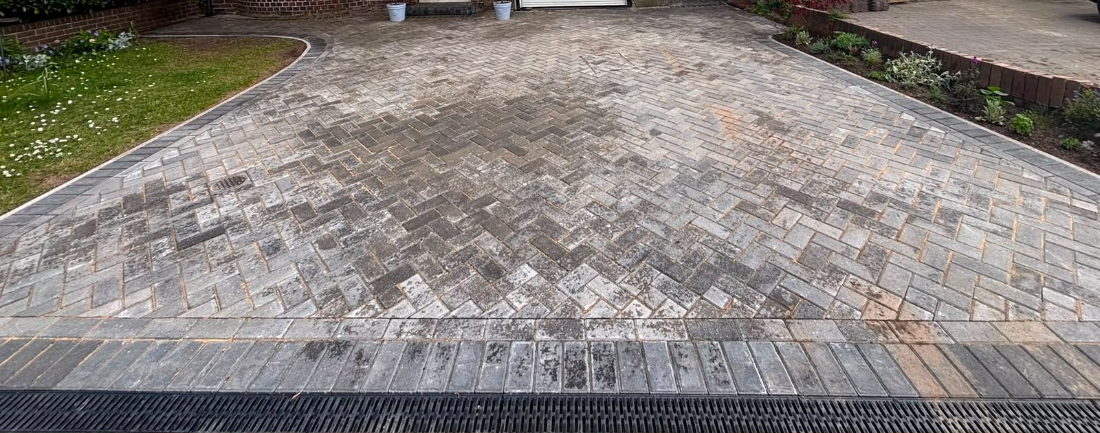 Grey herringbone block-paved driveway with dark border