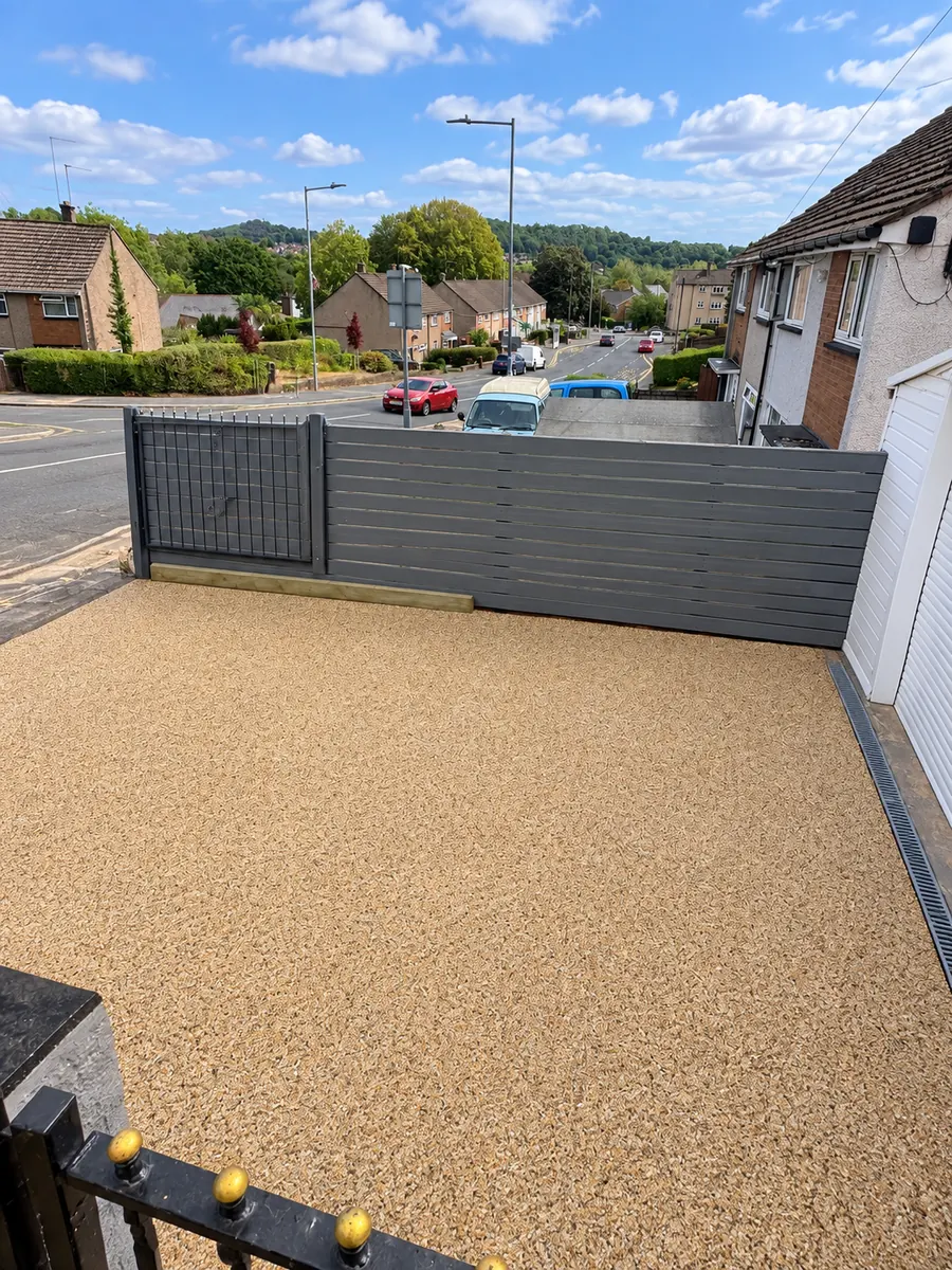 Resin driveway, grey boundary fence and linear drainage channel beside garage
