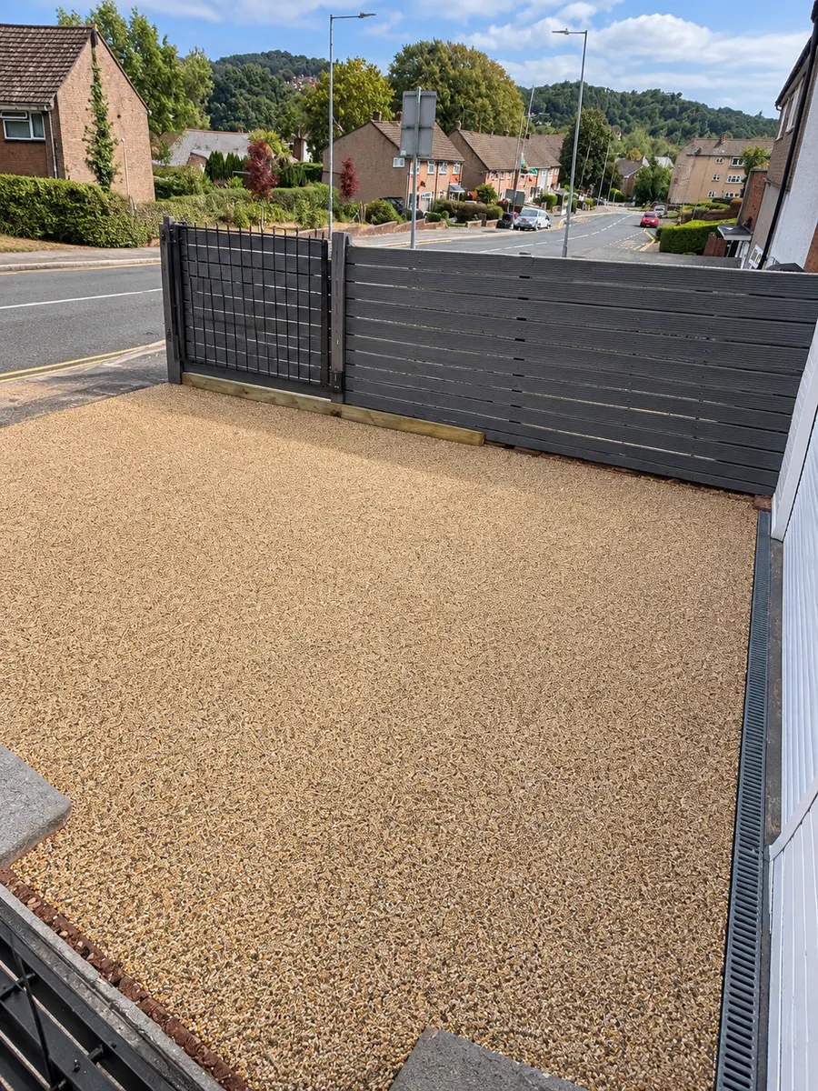 Resin driveway, grey fence and clearly visible linear drain beside garage