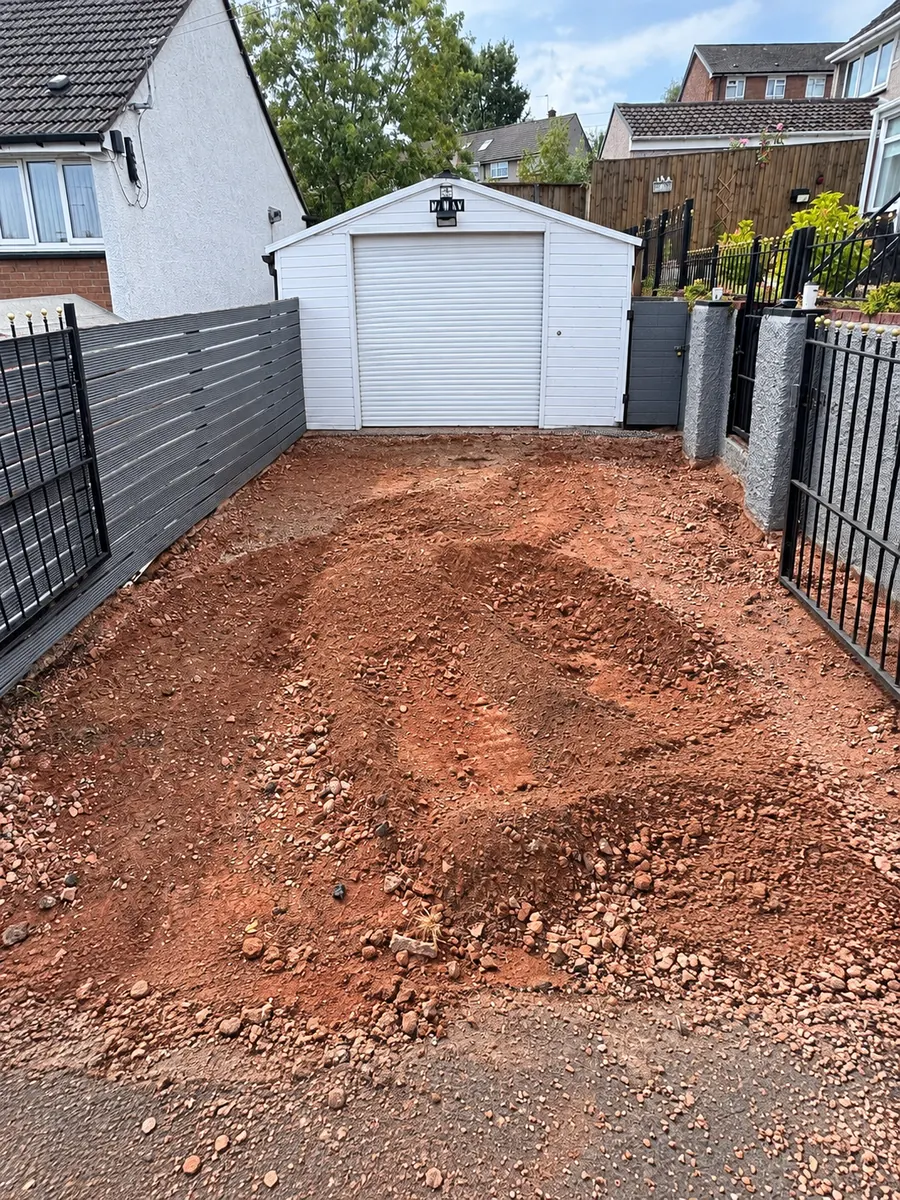 Excavated driveway with grey boundary fence and white garage