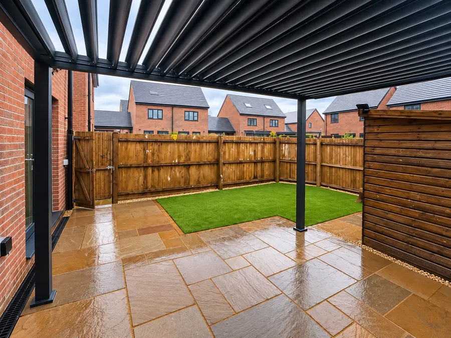 Pergola over sandstone patio beside artificial lawn and timber fencing