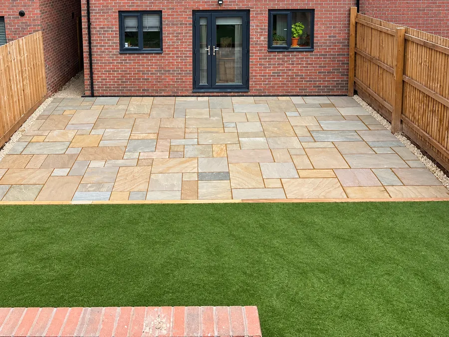 Sandstone patio, artificial lawn and timber boundary fence