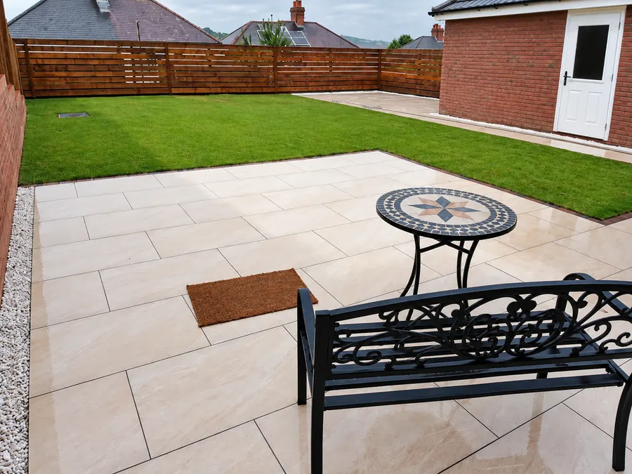 Large rear garden with sandstone patio, artificial lawn and dining furniture, finished by CoCo Gardens