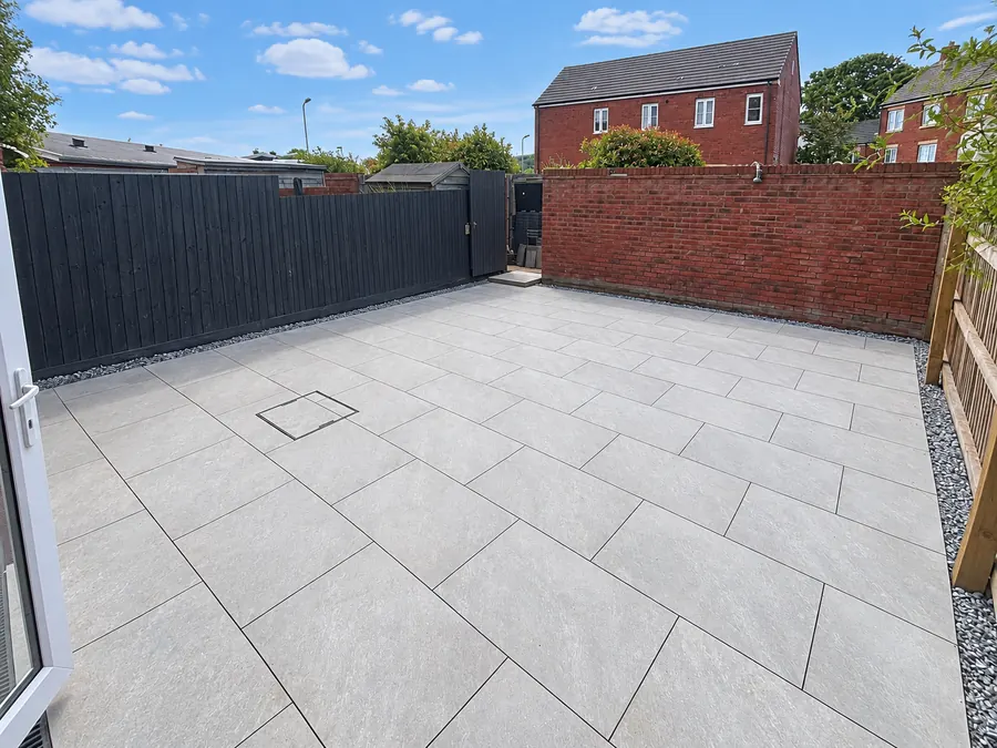 Grey slab patio and dark boundary fence/gate