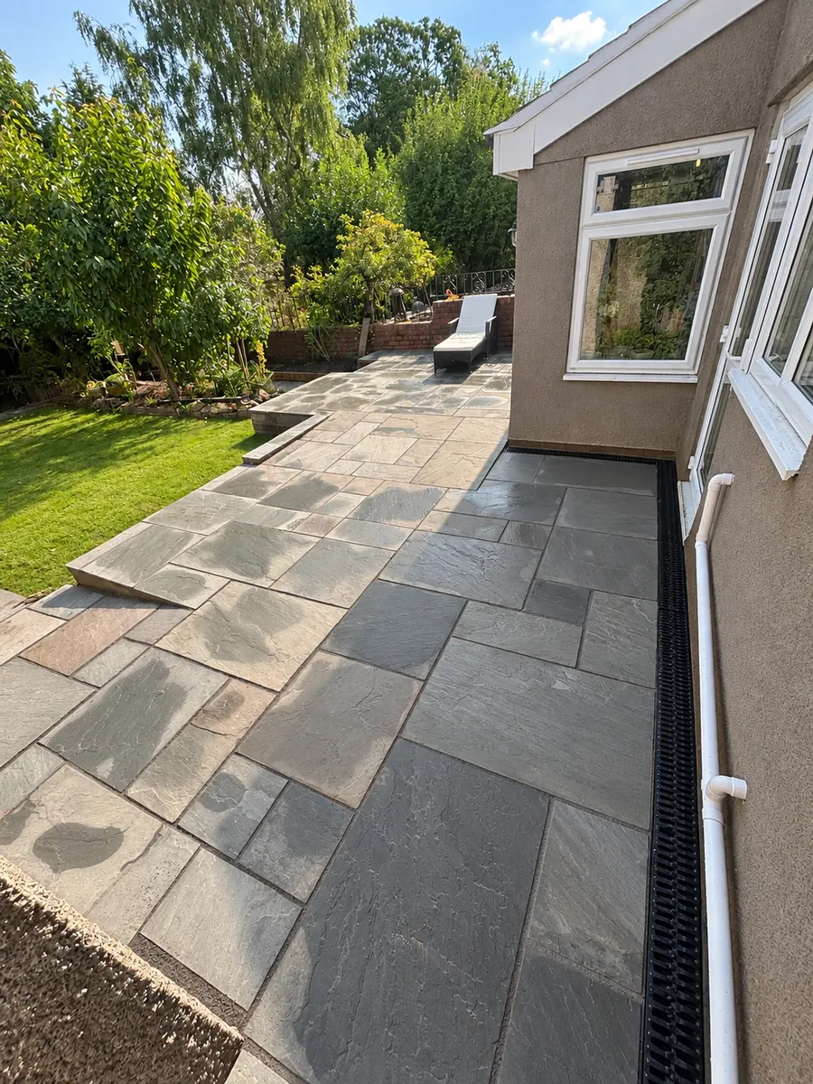 Raised stone slab patio and steps beside established lawn