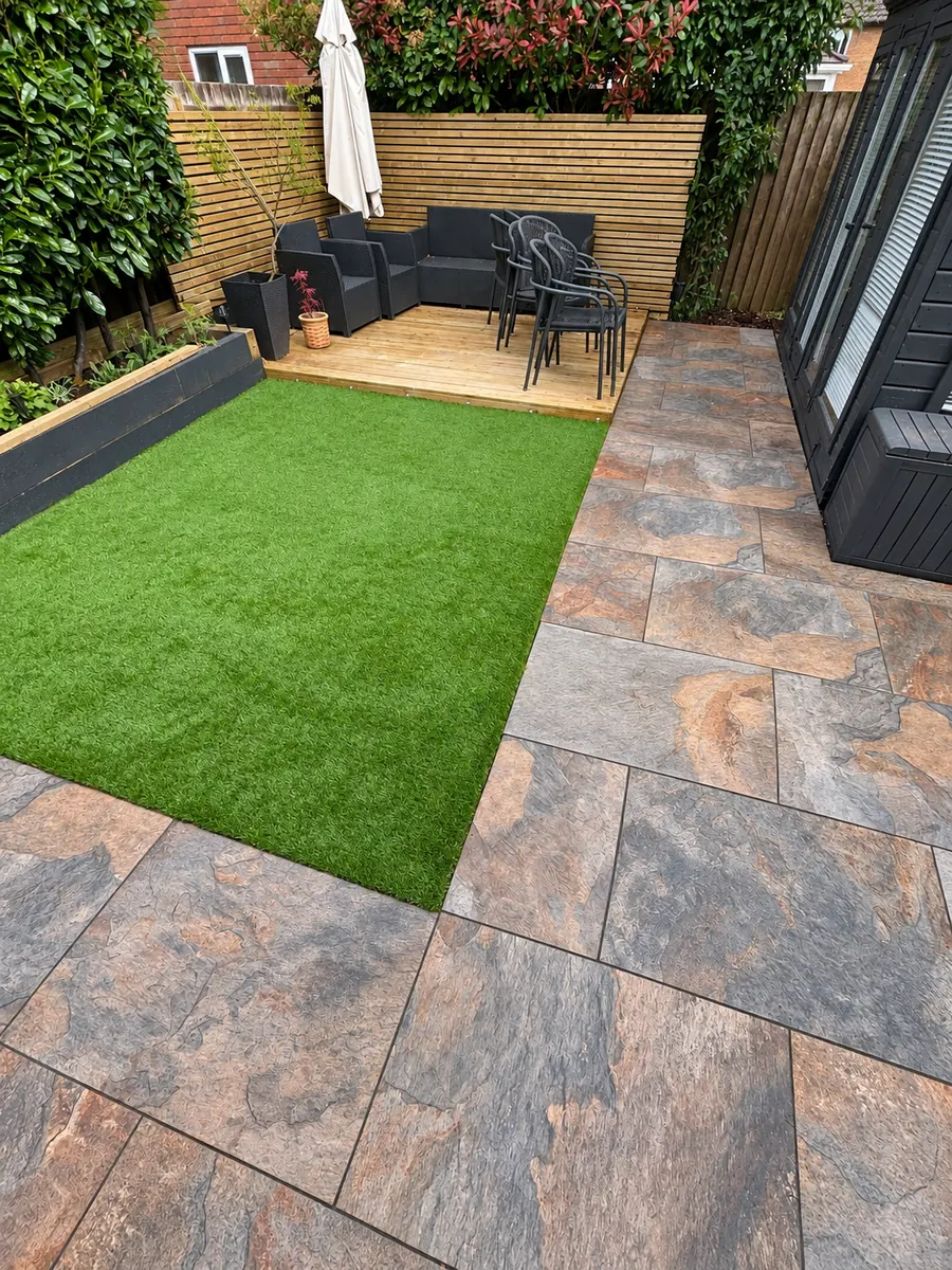 Multicolour stone slab patio, artificial lawn and timber fence beside summerhouse