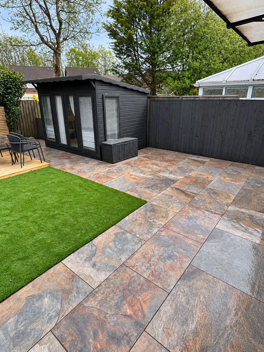 Multicolour slab patio and artificial lawn by black summerhouse