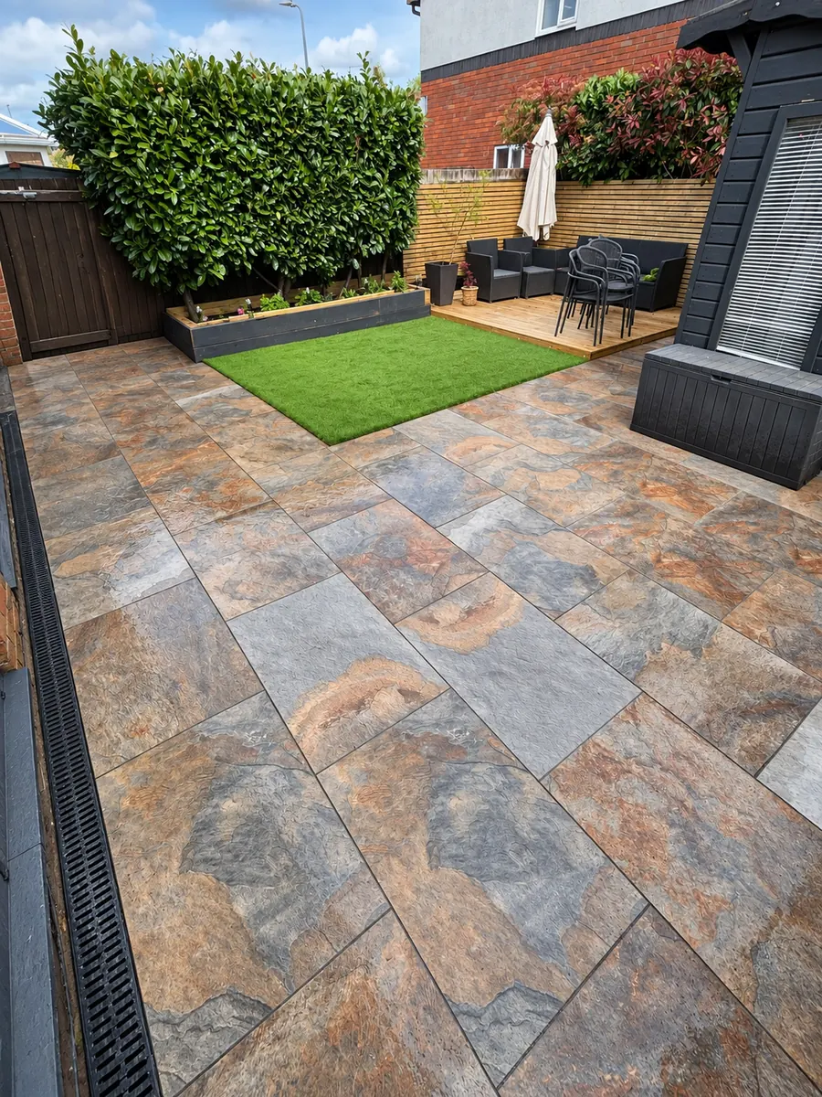 Wide view of multicolour slab patio, artificial lawn and timber fence