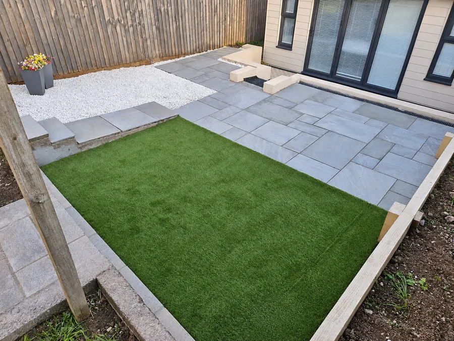 Finished grey slab patio, artificial lawn and white gravel area