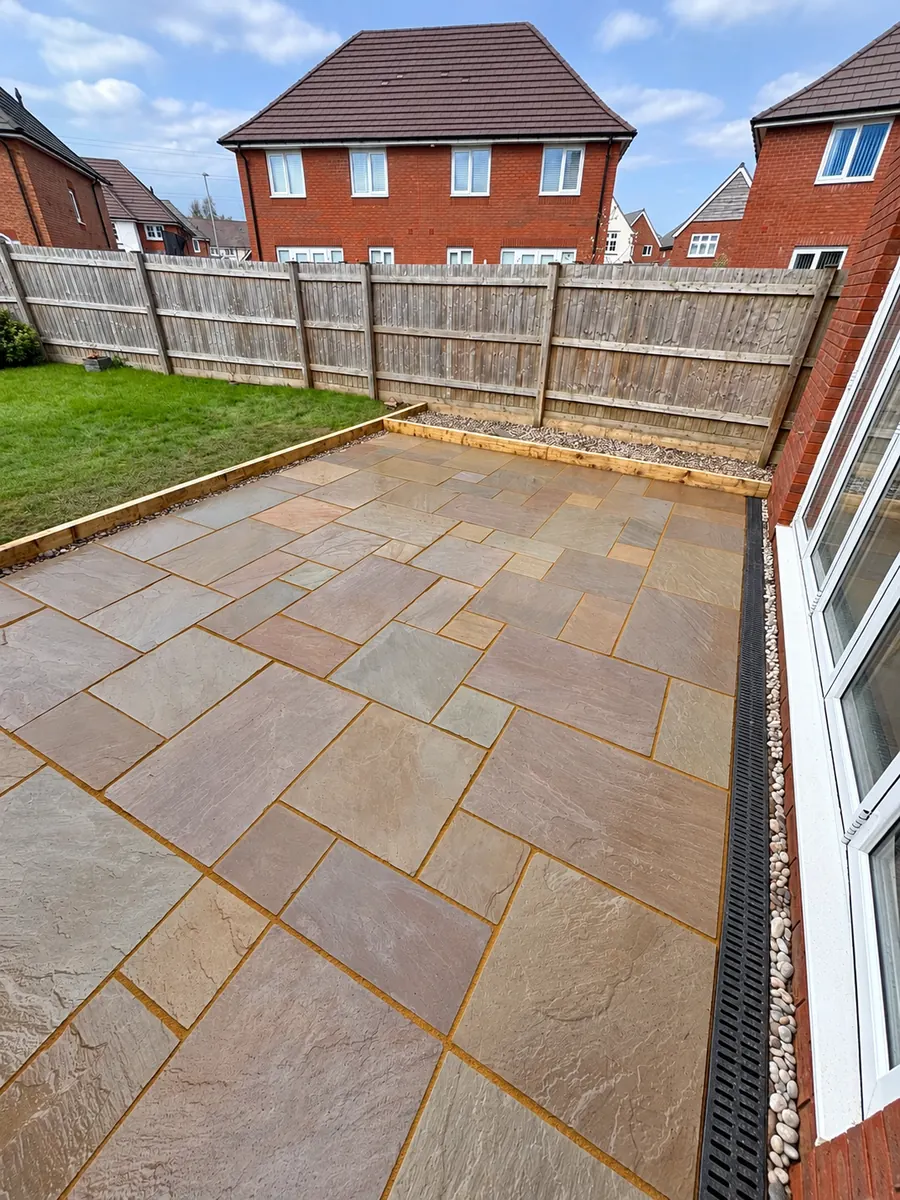 Finished sandstone patio beside lawn and timber sleeper edging